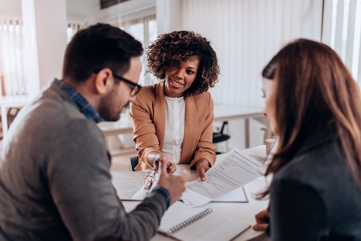 Three people discussing documents at table.