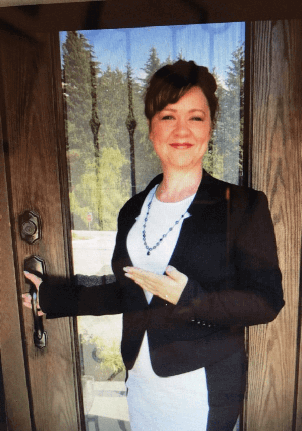 Smiling woman standing by a wooden door.