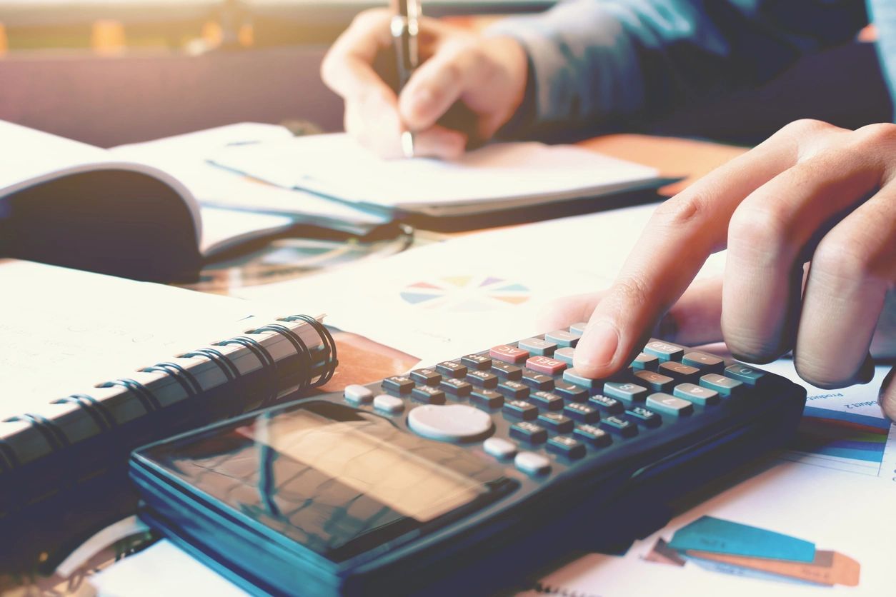 Person using calculator and writing notes.